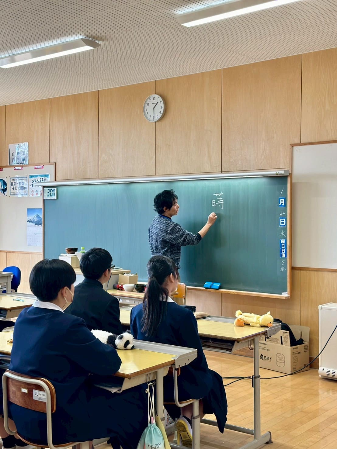 生徒たちの前で黒板に蒔絵と書く写真